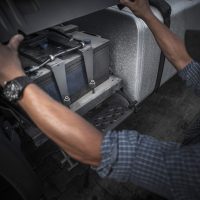 Checking on Truck Battery. Trucking Concept Photo. Caucasian Truck Driver Opening Vehicle Battery Compartment.