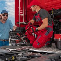 Trucker and Professional Truck Mechanic Making Conversation Regarding Semi Truck Technical Issue. Heavy Duty Transportation Theme.